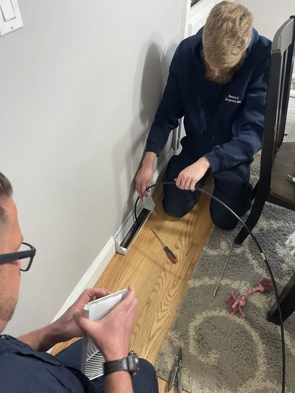 Donovan & Jorgenson Heating and Cooling tech doing duct cleaning inside a home in Mukwonago, WI